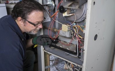 Furnace repair worker servicing electronics